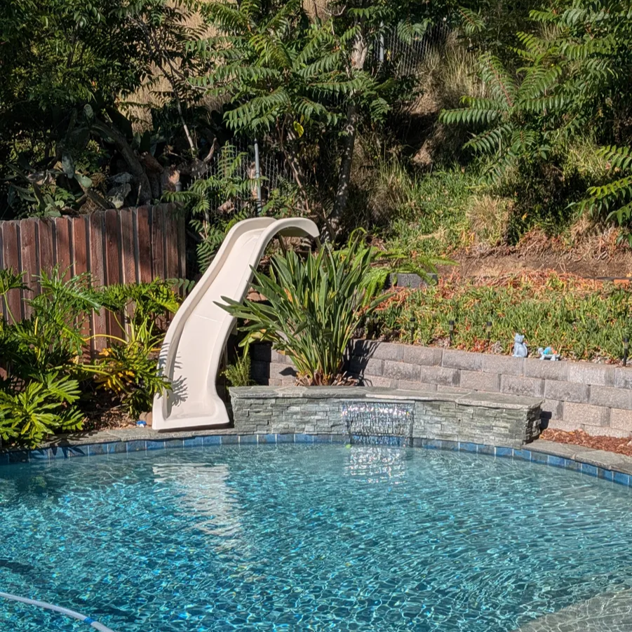 Swimming pool with a slide surrounded by greenery